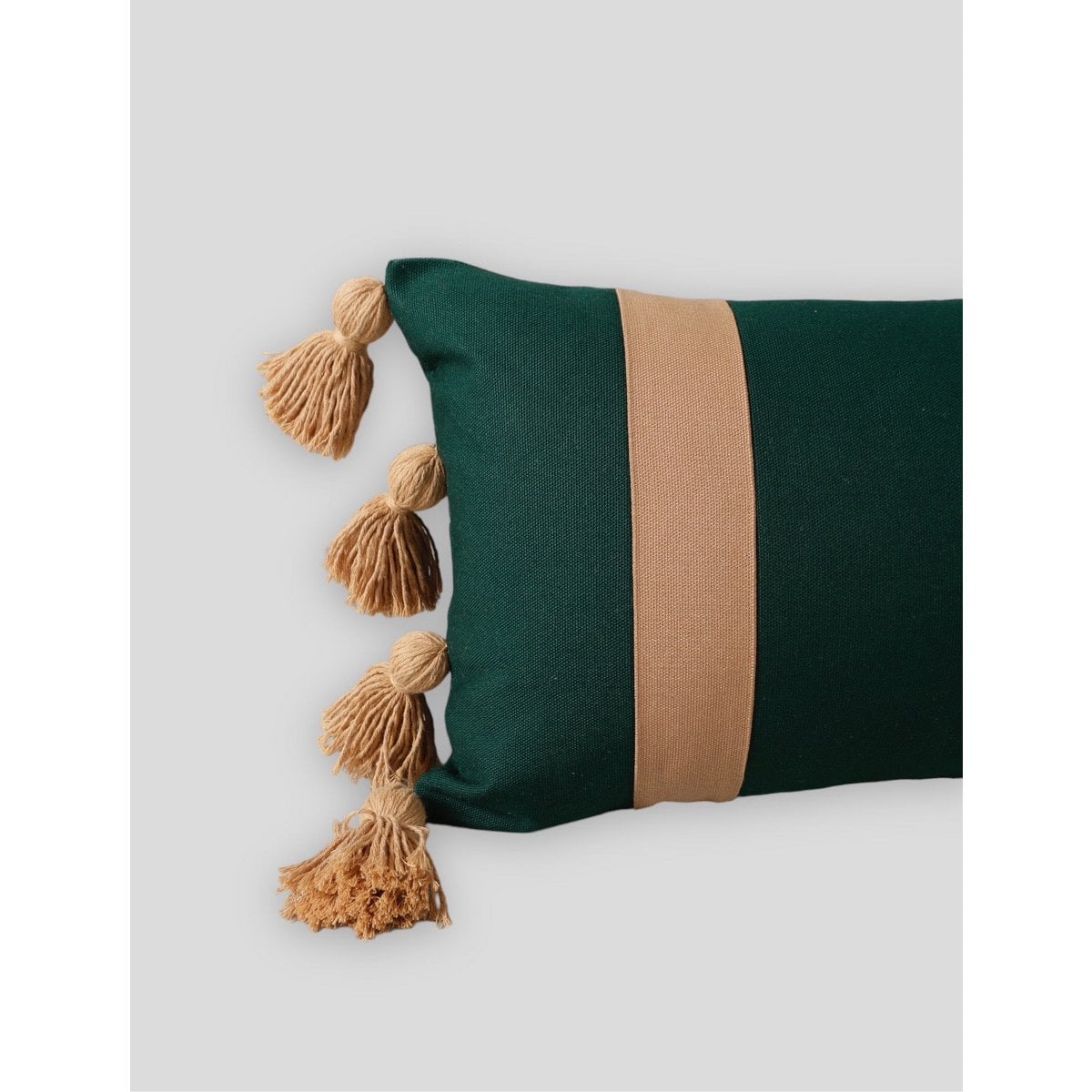 Green pillow with a brown stripe and tassels on a light gray background