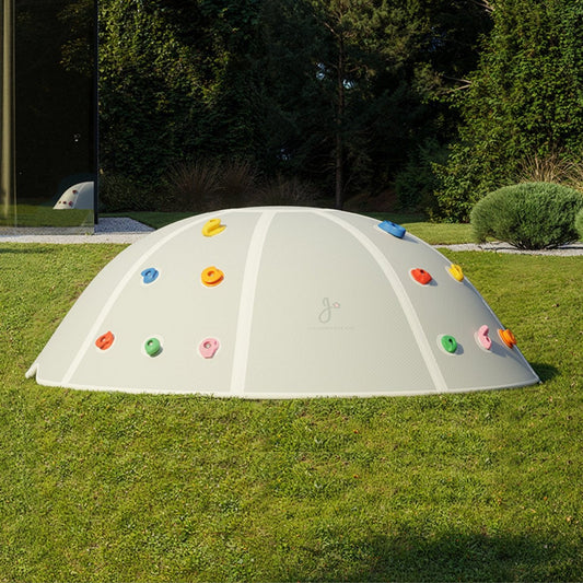 Children's play dome with colorful climbing holds on a grassy area