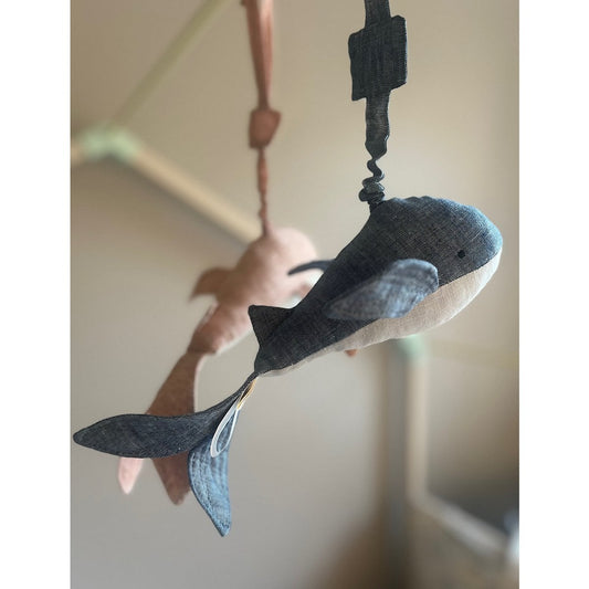Decorative whale hanging from a rope against a neutral background