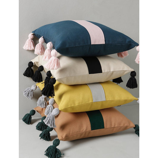 Stack of colorful pillows with tassels on a neutral background