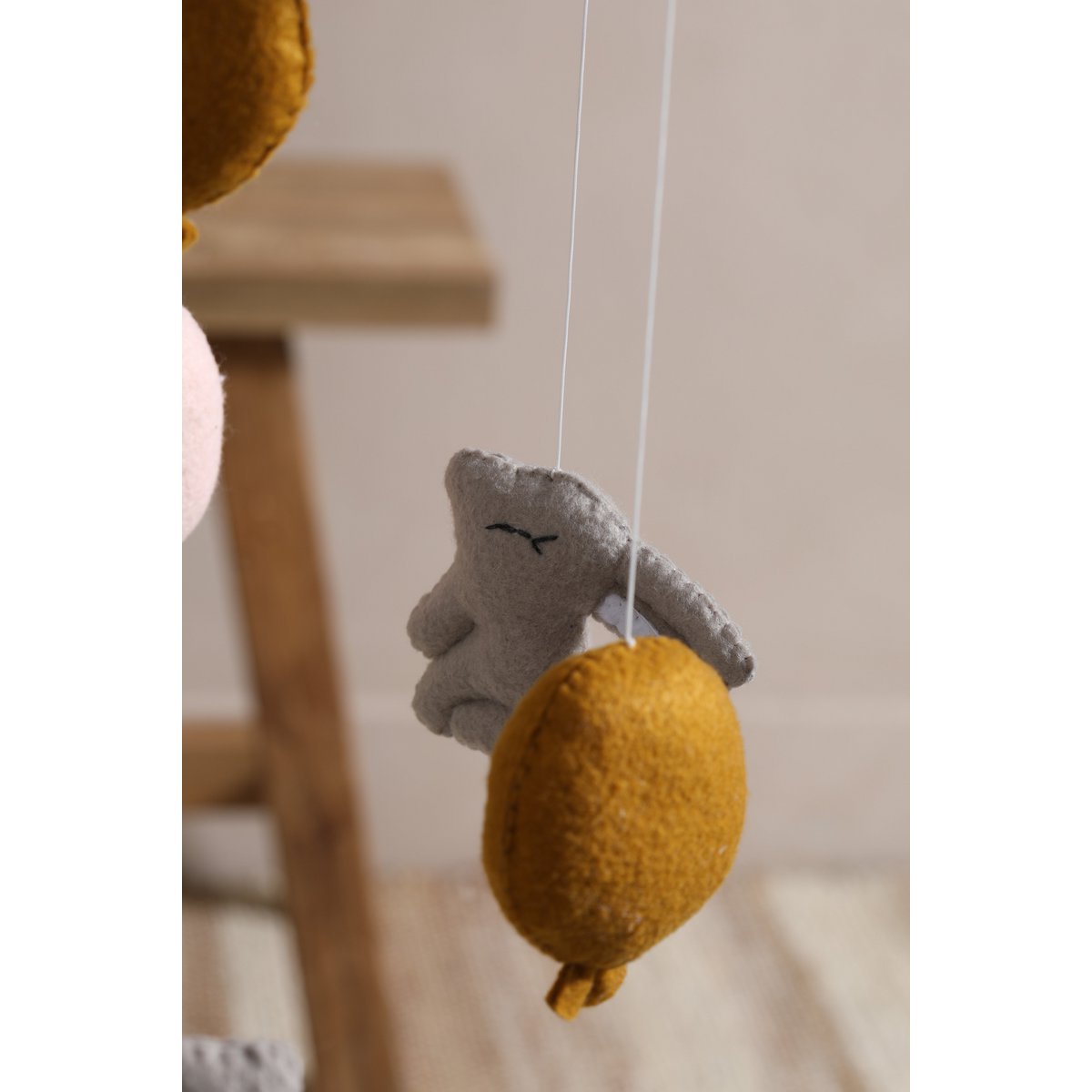 Decorative hanging mobile with a gray face and yellow ball on a white background
