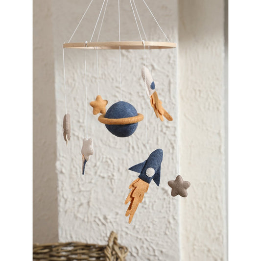 Children's space-themed mobile with planets, rockets, and stars hanging against a textured wall.