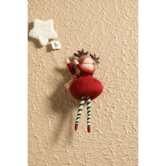 Small stuffed reindeer toy hanging on a textured beige wall with a white star above it.