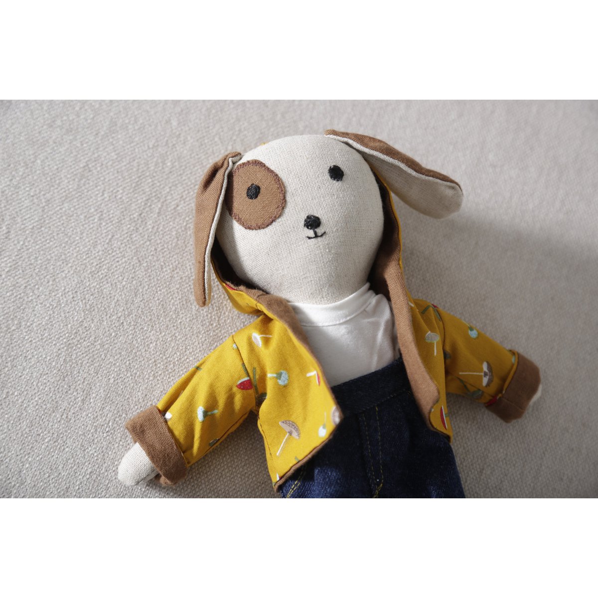 Stuffed animal toy with a yellow raincoat on a plain background