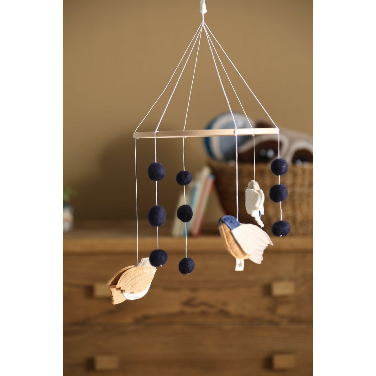 Decorative hanging mobile with birds and black spheres on a wooden surface.