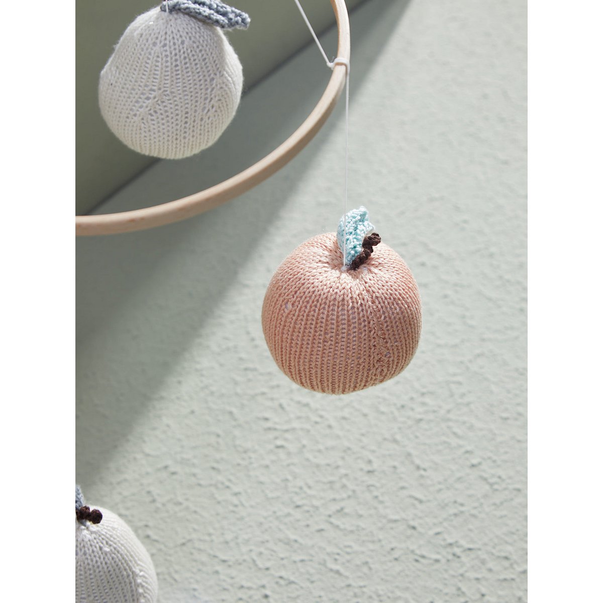 Knitted pumpkin ornament on a light green surface