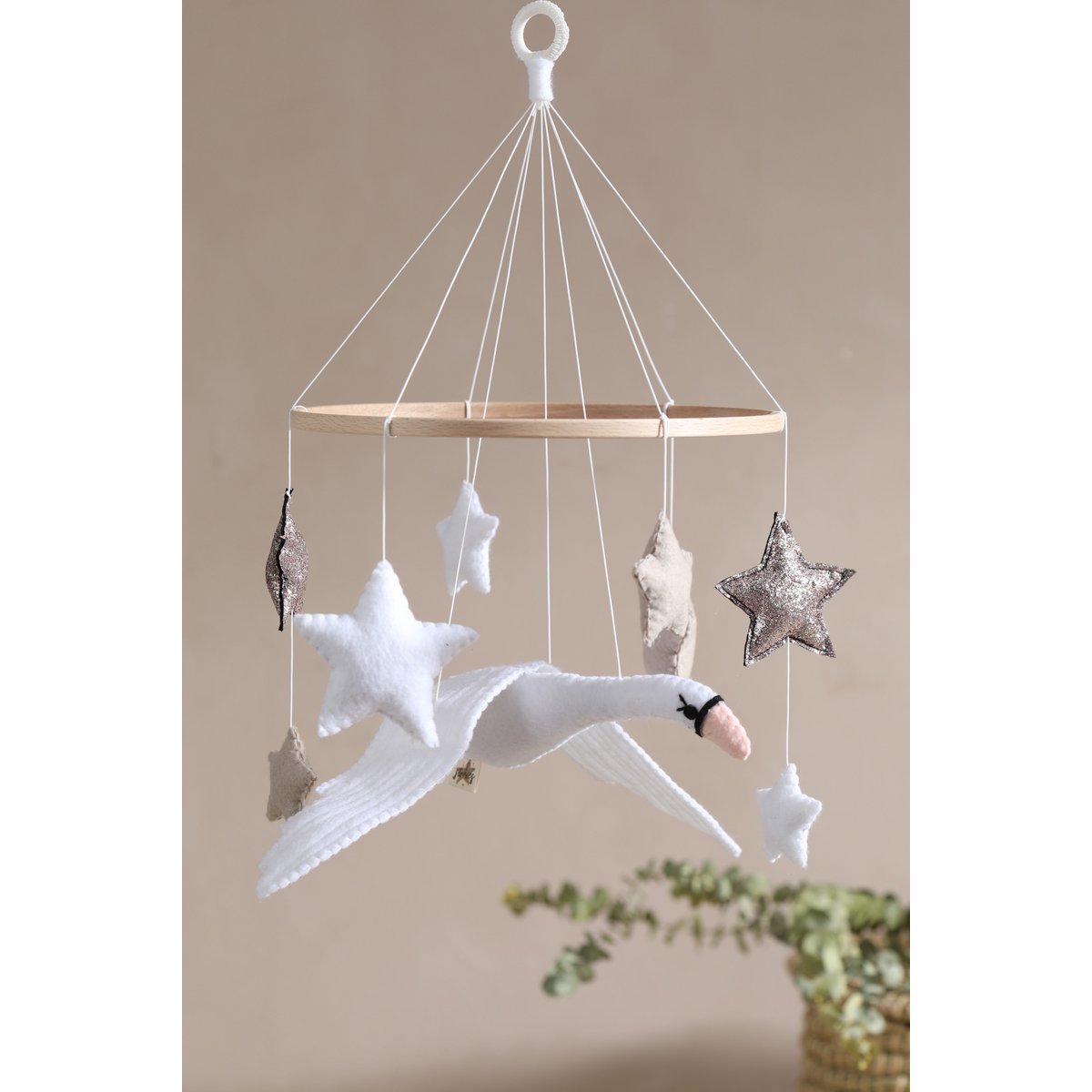 Decorative hanging mobile with stars and a swan against a beige background