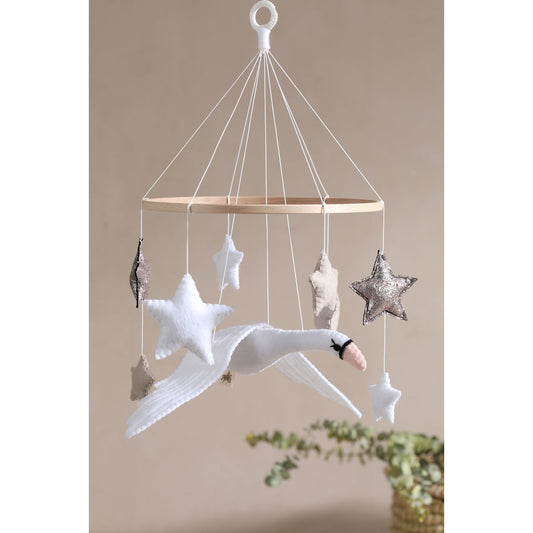Decorative hanging mobile with stars and a swan against a beige background