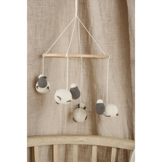 Baby crib mobile with sheep designs hanging against a neutral curtain background