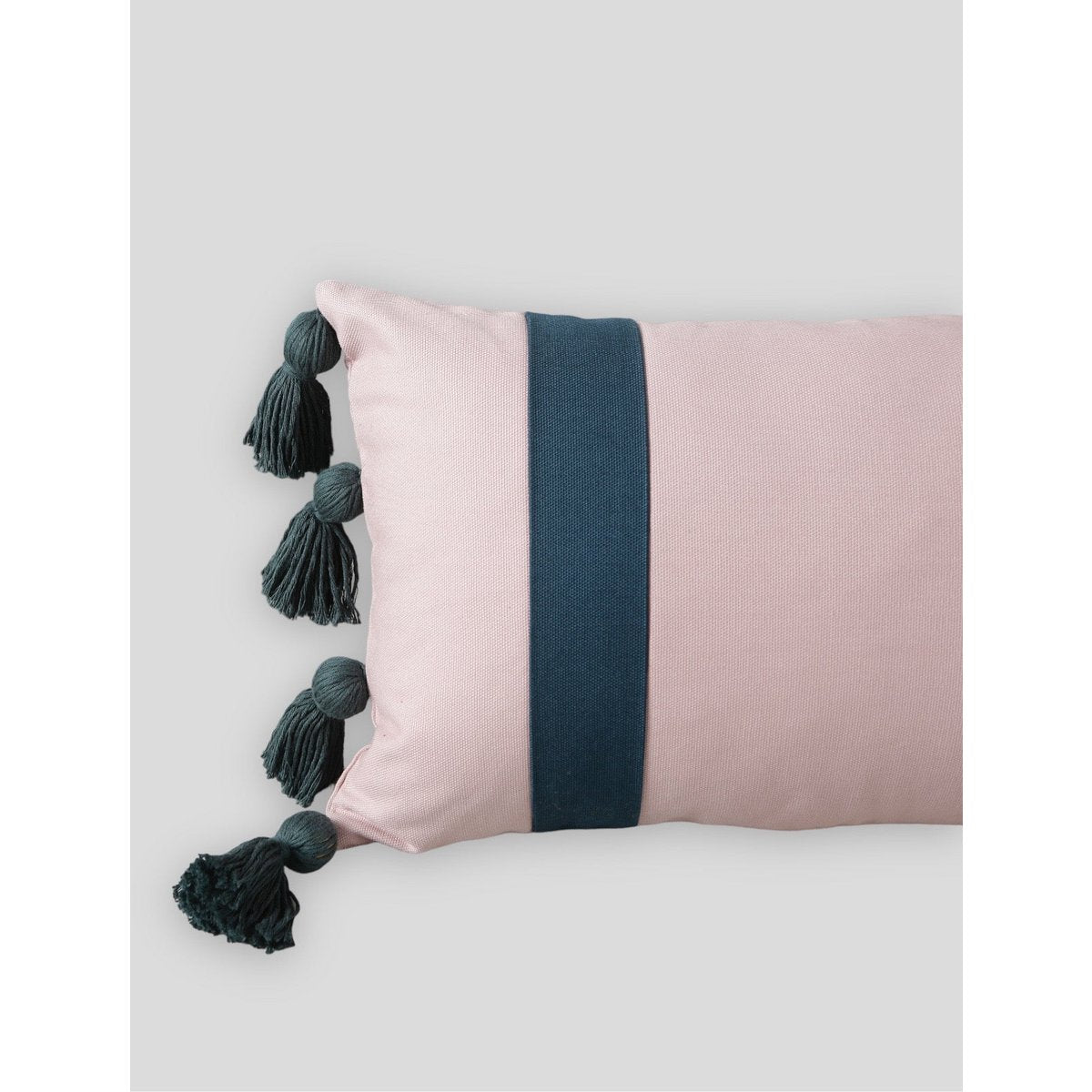 Pink pillow with a navy band and tassels on a light gray background