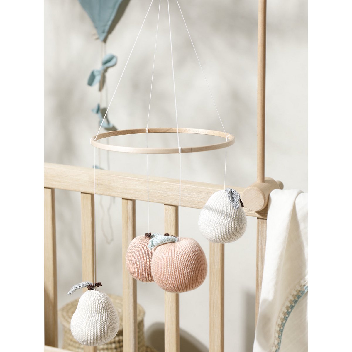 Knitted baby mobile hanging above a crib with neutral colors.