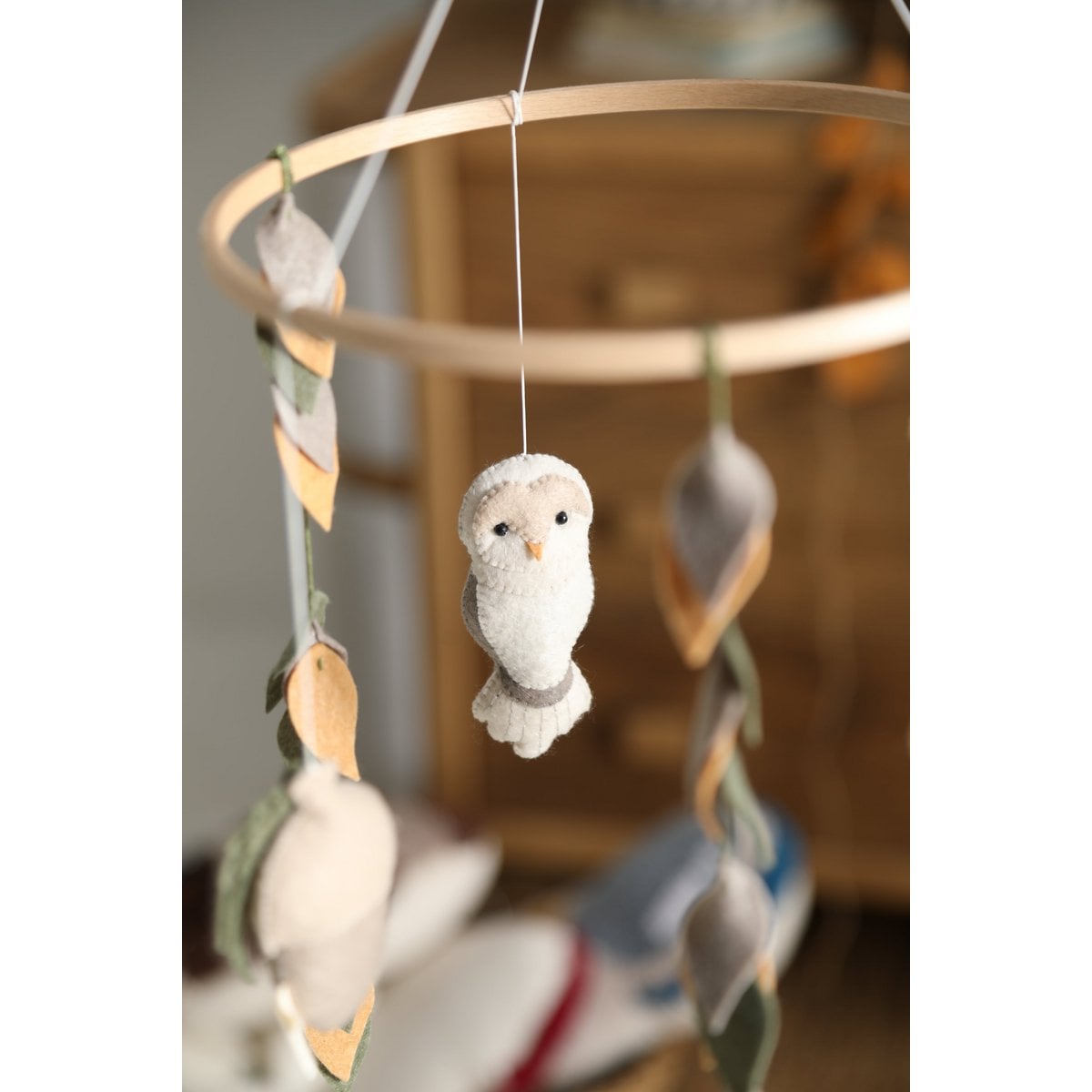 Decorative mobile with hanging owl toy against a blurred background
